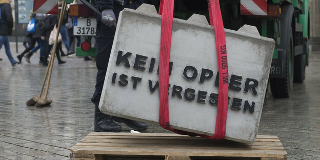 Ein Betonblock mit der Aufschrift "Kein Opfer ist vergessen" wird entfernt