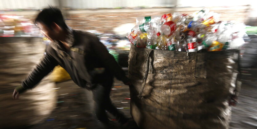 Ein Mann zieht einen großen Sack mit Plastikflaschen