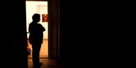 Eine Frau steht im Dunkeln vor einer geöffneten Tür