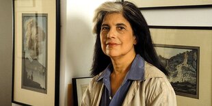 Susan Sontag steht vor gerahmten Bildern