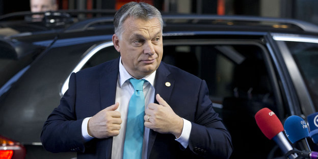 Orban steigt aus einem Auto und rückt sich die Jacke zurecht