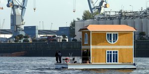 Ein gelbes Hausboot fährt durch den Hamburger Hafen.