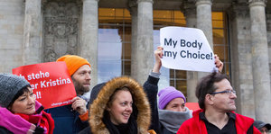 Demonstrantinnen stehen nebeneinander, eine hält ein Blatt mit der Aufschrift „My Body, my Choice“ hoch