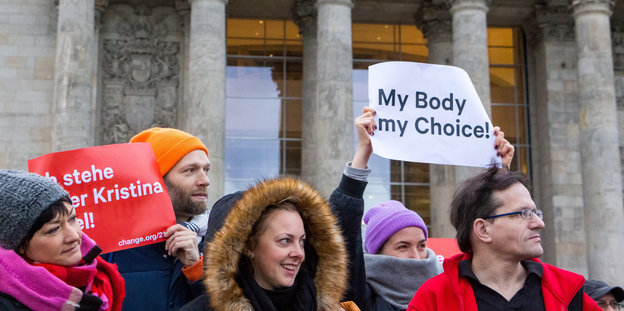 Demonstrantinnen stehen nebeneinander, eine hält ein Blatt mit der Aufschrift „My Body, my Choice“ hoch