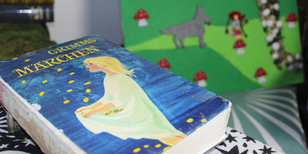 Ein Buch auf einem Tisch. Auf dem Titelbild sieht man ein Mädchen, das Sterne, die herunter fallen mit seinem Kleid auffängt