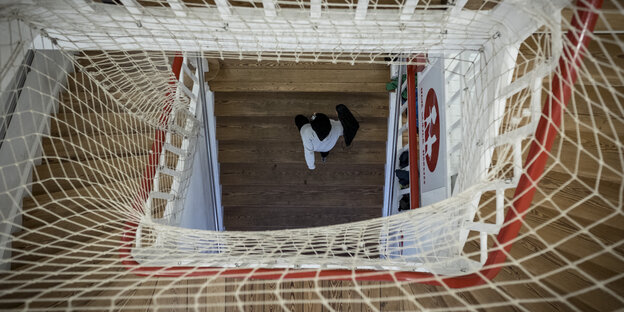 Ein Schüler geht eine Treppe hoch, deren Geländer mit einem Netz abgesichert ist.