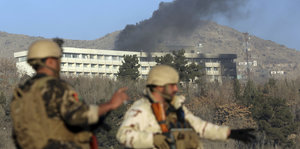 Zwei Soldaten, im Hintergrund ein brennendes Gebäude