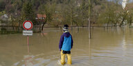 Ein Mensch in Anglerhosen steht im Hochwasser