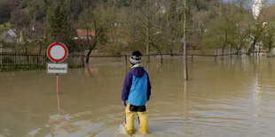 Ein Mensch in Anglerhosen steht im Hochwasser