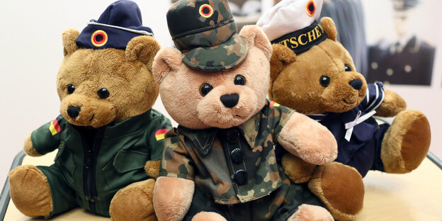 Drei Teddybären in Uniform sitzen nebeneinander