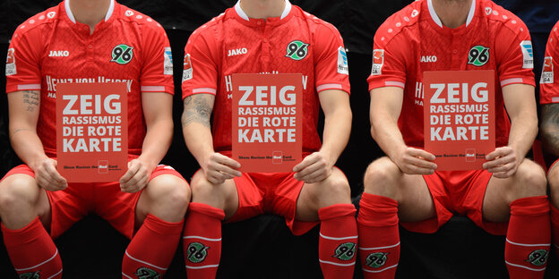 Spieler von Hannover 96 halten Karten mit dem Schriftzug "Zeig Rassismus die rote Karte".