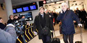 Zwei Männer mit Rollkoffern in einem Flughafenterminal