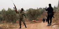 Ein Kämpfer der Freien Syrischen Armee schießt in die Luft, ein anderer steht neben ihm