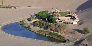 Häuser und Bäume an einem See umgeben von viel Sand