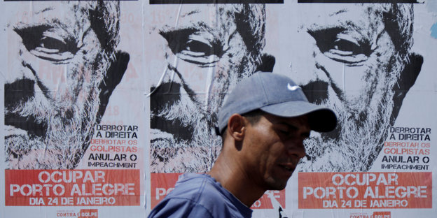 Ein Mann vor Plakaten, die zur Unterstützung Lula da Silvas aufrufen.