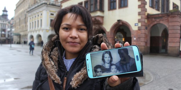 Theresa Hahnsch, Tochter eines mosambikanischen Vertragsarbeiters und einer deutschen Mutter, zeigt in Leipzig ihr Smartphone mit einem Foto ihrer Eltern