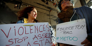 Zwei Frauen halten Schilder mit den Worten "Gewalt. Stop. Genug!" und dem Hashtag #BalanceTonPorc, der französischen Variante von #MeToo