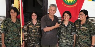Ein Mann in zivil steht zwischen vier Frauen in Militäruniformen.