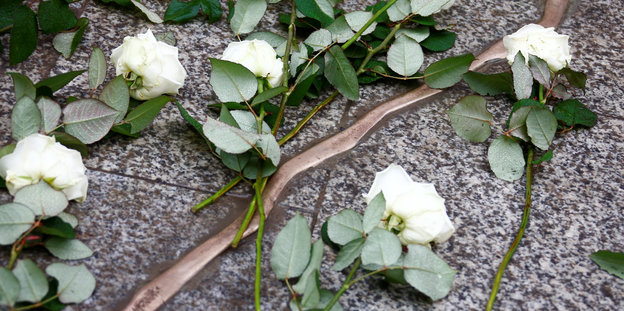 Ein blitzartiges Mahnmal am Boden des Breitscheidplatzes, darauf liegen weiße Rosen