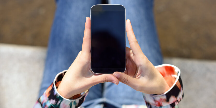 Eine Frau hält ein Smartphone in ihren Händen