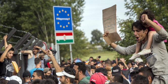 Menschen protestieren vor einem Zaun