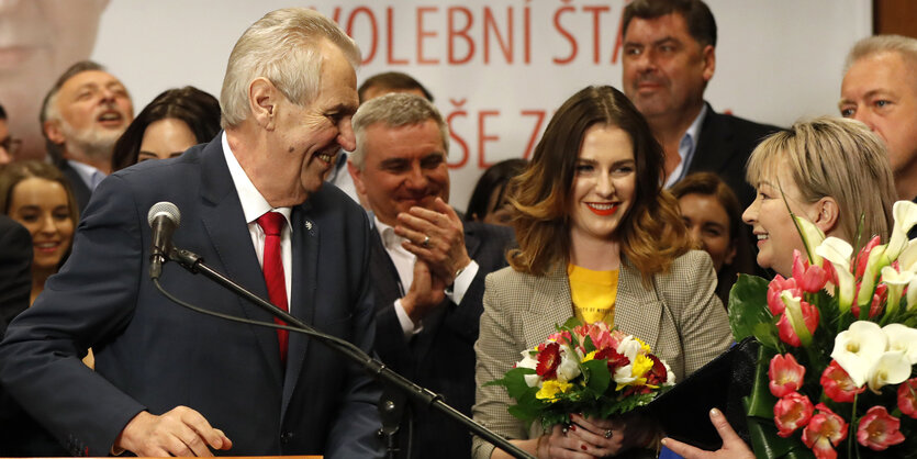 Applaudierende Menschen mit Blumen auf einer Bühne