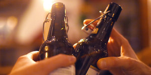 Zwei Personen stoßen mit Bierflaschen an
