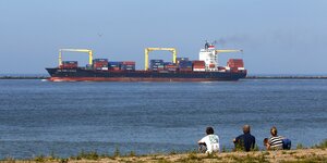 drei Menschen beobachten Containerschiff bei Rotterdam