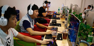 Chinesische Jugendliche mit Kopfhörern vor Bildschirmen in einem Internet-Cafe'