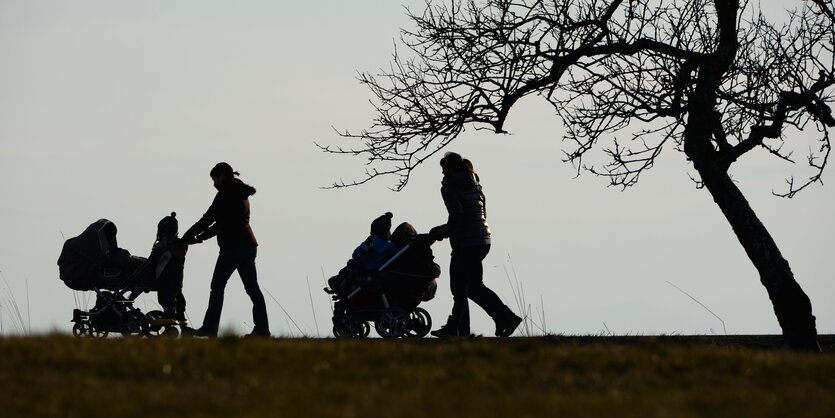 Zwei Frauen schieben ihre Kinderwagen in der Dämmerung.