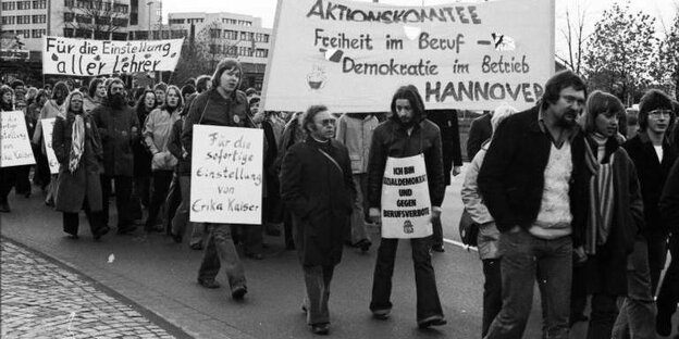 Eine Menschenmenge mit Plakaten geht auf einer Straße in Oldenburg. Die Plakate wenden sich gegen Berufsverbote.