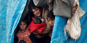 Syrische Kinder schauen aus einem Zelt nahe der Grenze zur Türkei