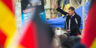 Björn Höcke spricht an einem Rednerpult im Freien, davor stehen Menschen mit Deutschlandfahnen