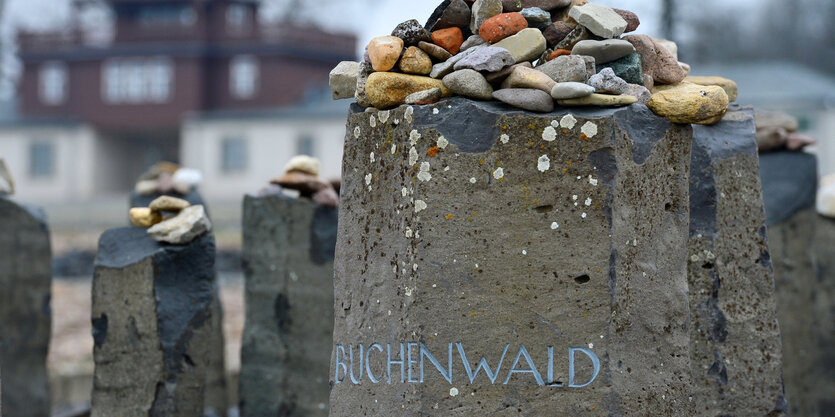 Kleine Steine liegen auf einem Gedenkstein mit der Aufschrift „Buchenwald“