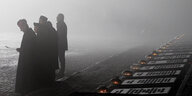 Menschen stehen in Nebel an der Gedenkstätte des ehemaligen Konzentrationslagers Auschwitz