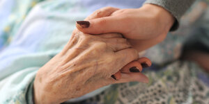 Eine junge Frau hält die Hände einer alten Frau