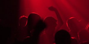 Menschen tanzen in einem düsteren Raum in rötlichem Licht