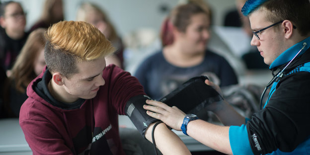 Ein Schüler legt einem anderen ein Blutdruckmessgerät an