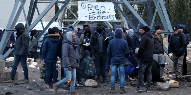 Geflüchtete im Flüchtlingscamp in Calais (Frankreich) in einer Gruppe unter dem Banner «Öffnet die Grenzen»