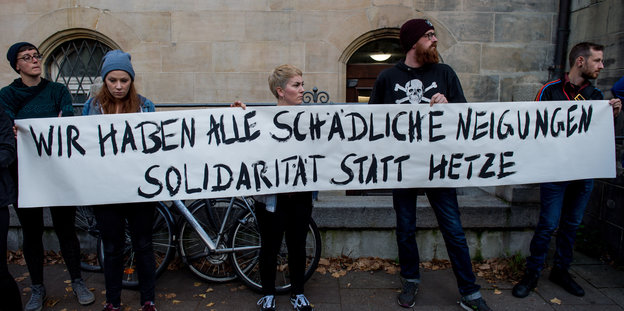 Fünf junge Leute stehen vor der Mauer eines alten Gebäudes und tragen ein Transparent, auf dem steht: "Wir haben alle schädliche Neigungen. Solidarität statt Hetze."