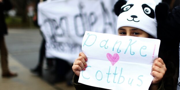 Ein Kind mit einem Schild, auf dem „Danke Cottbus“ steht