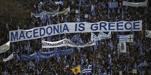 Viele Menschen halten Banner und blau-weiße Fahnen in die Höhe. in der Mitte des Bildes ist ein übergroßes Banner mit der Aufschrift "Macedonia is Greece" zu sehen