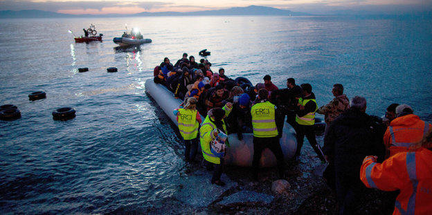 Helfer helfen Menschen aus einem Flüchtlingsboot