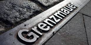 Grenzmauer steht auf einer Metallplatte