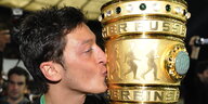ein Mann küsst einen großen goldenen Pokal