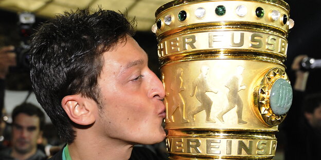 ein Mann küsst einen großen goldenen Pokal