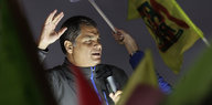 Rafael Correa hält eine Rede, viele Menschen um ihn schwenken Fahnen