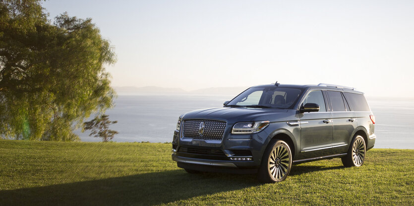 Ein SUV auf einer grünen Wiese vor einem See