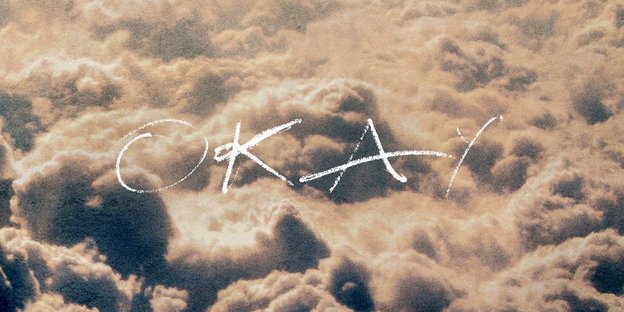 Wolken von oben fotografiert darauf der Schriftzug „Okay“