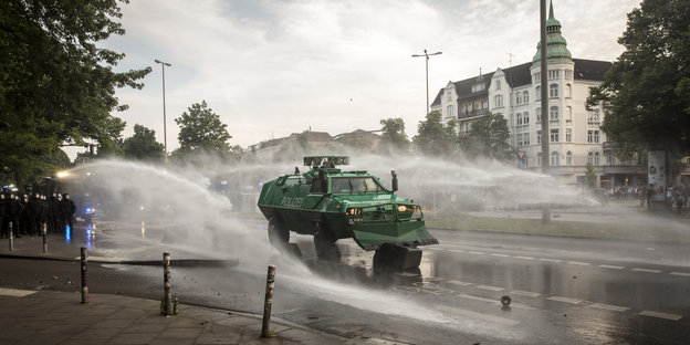 Ein Räumfahrzeug der Polizei schiebt flaniert von zwei Wasserwerfern eine Mülltonne von einer Straße in Hamburg.